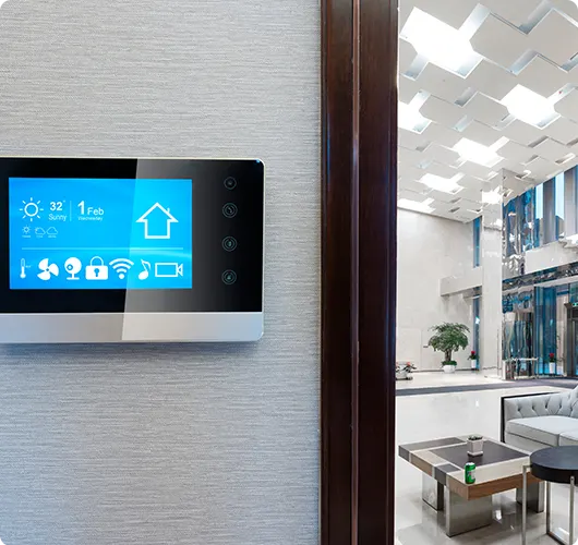 A wall-mounted touchscreen control panel in a modern lobby for home automation.